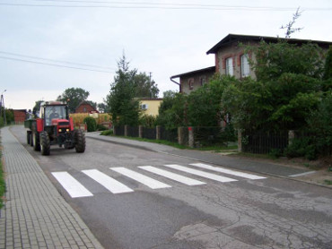 Widok na ulicę z chodnikiem z polbruku i oznakowane przejście dla pieszych - zebra